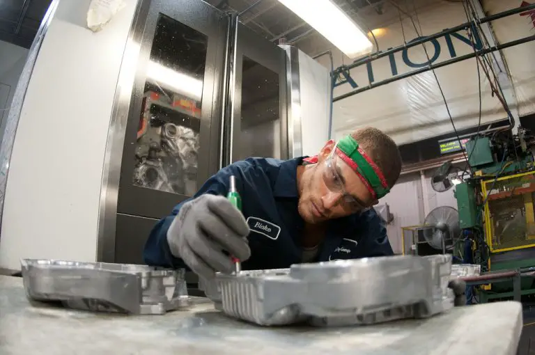 cnc operator inspecting part in front of machine