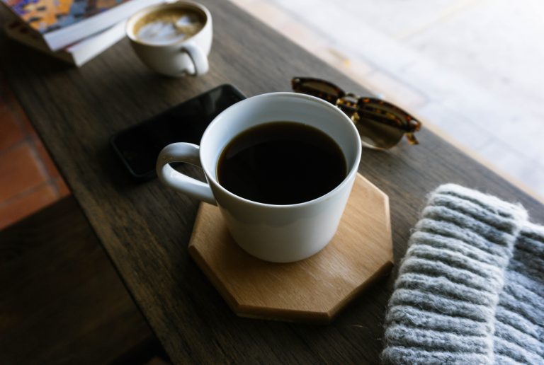 a cup of coffee sitting on a wooden coaster