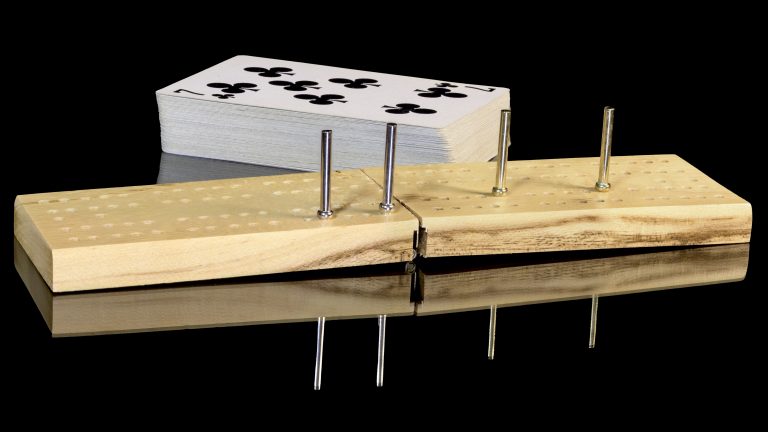a wooden cribbage board with a deck of cards