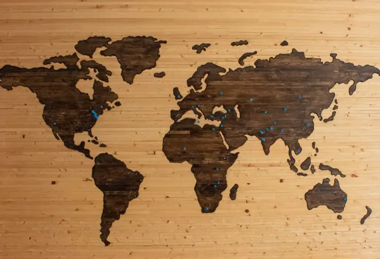 a wooden map with blue pushpins in some locations