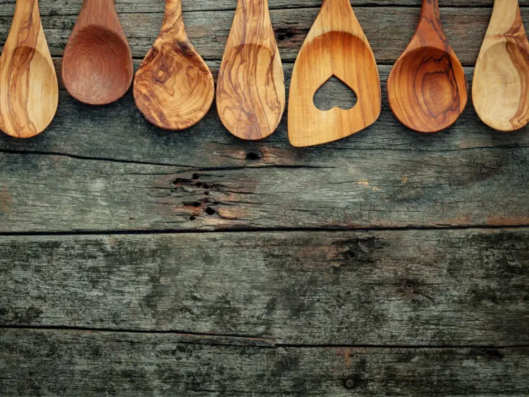 multiple wooden spoons lined up on a wood background