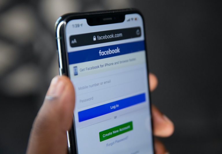 hand holding a phone that shows the facebook login page